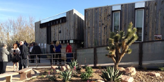 Photo of a modern house with people and cactus in front.