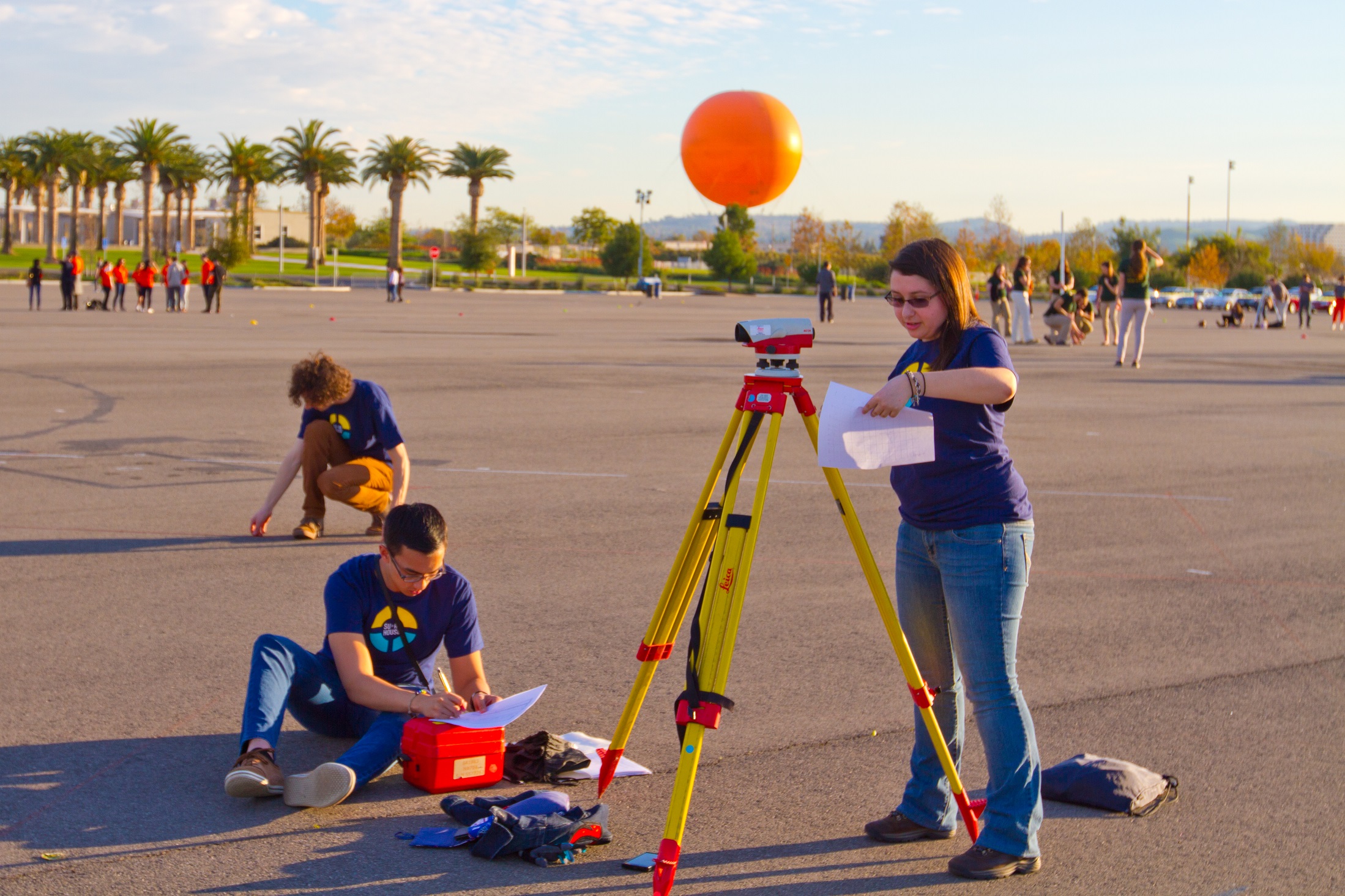 Photo of two people taking measurements with surveying equipment on a tripod.