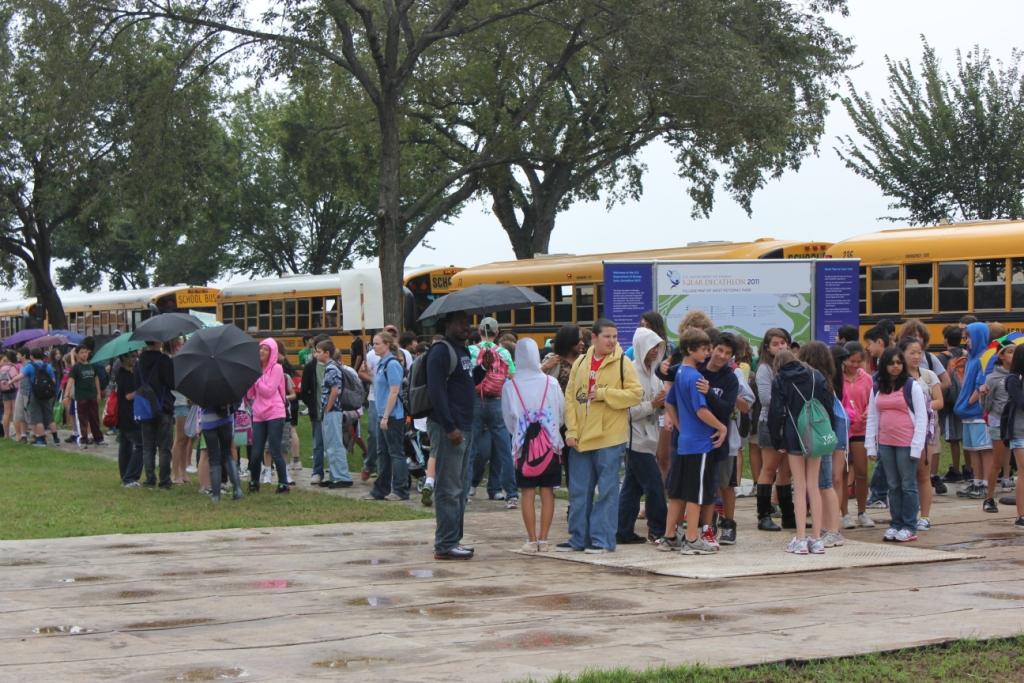 Photo of a large group of students lined up in front of buses.