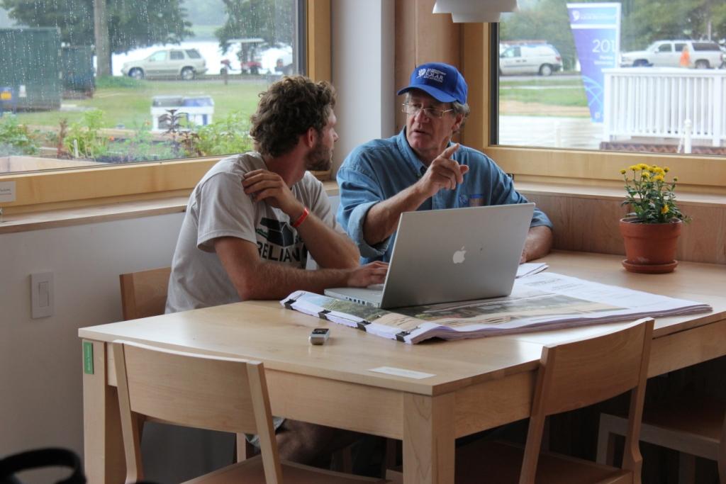 Photo of a student decathlete reviewing construction documents and online data with Matt Hansen.