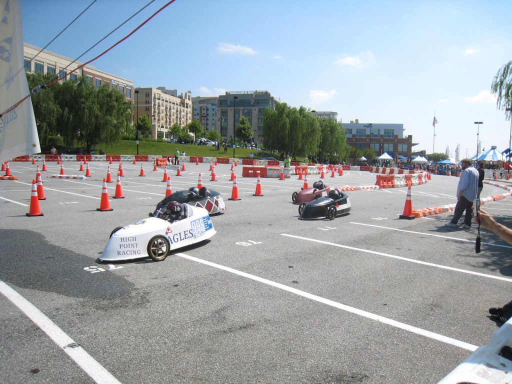 Photo of electrathon vehicles racing on course marked by traffic cones.