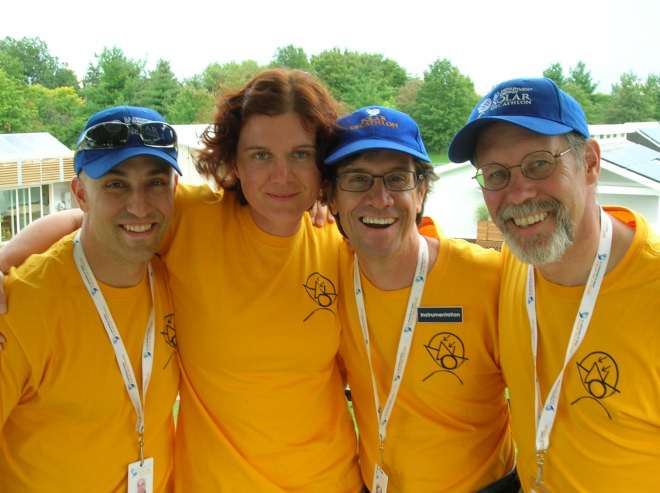 Photo of three men and one woman wearing gold shirts and Solar Decathlon hats.