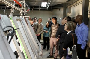 Photo of a group of people looking at solar panels in a small room.