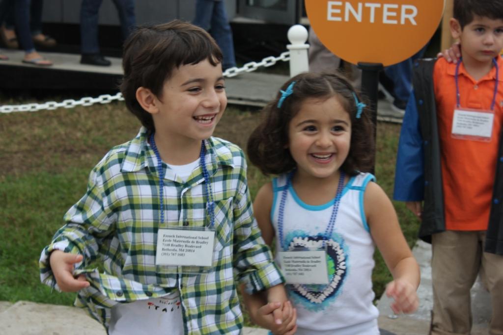 Photo of two children smiling and holding hands after leaving a competition house.