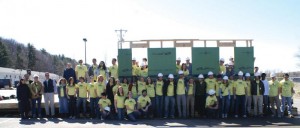 Photo of a group of people standing in front of a single erect wall frame. 