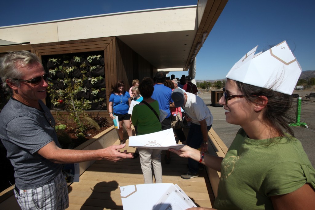 Photo of Sandra Violand distributing handouts to visitors in line at the LISI house.