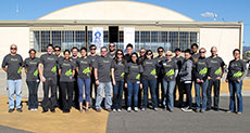 Photo of the Arizona State University and The  University of New Mexico Solar Decathlon 2013 team standing in front of an  airplane hangar. 