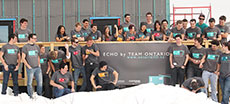 Photo of members of the Queen's University, Carleton  University, and Algonquin College Solar Decathlon 2013 team on the deck of  their partially constructed house. Several members are laughing and throwing  snowballs.