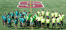 Photo of members of the Stevens Institute of Technology  Solar Decathlon 2013 team standing on an athletic field marked with the letter  S.