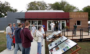 Photo of people reading exhibit panels in front of a home.