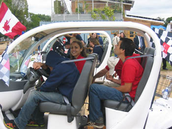 Photo of electric car, with Canadian flag flying, carrying a group of students.
