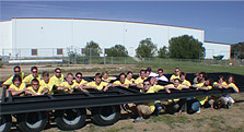 Photo of Cal Poly's 2005 Solar Decathlon team crouching inside the framework of a flatbed trailer.