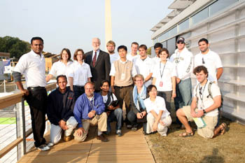 Photo of about 20 people assembled for a group photo on a deck outside of a futuristic-looking home with the Washington Monument in the background.