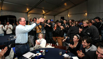 Photo of Richard King clapping with his arms outstretched as a room of standing students applauds him.
