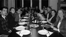 Photo of 16 members of Team Ontario/BC gathered around a long dining table. In front of each person is a plate, glass, and utensils.