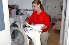 Photo of a woman placing towels in a washing machine.