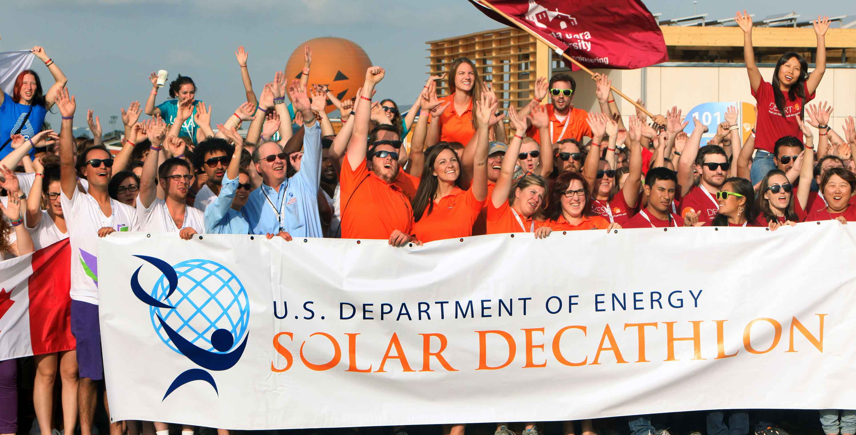 Photo of a group of decathletes cheering and holding a banner that says "U.S. Department of Energy Solar Decathlon."