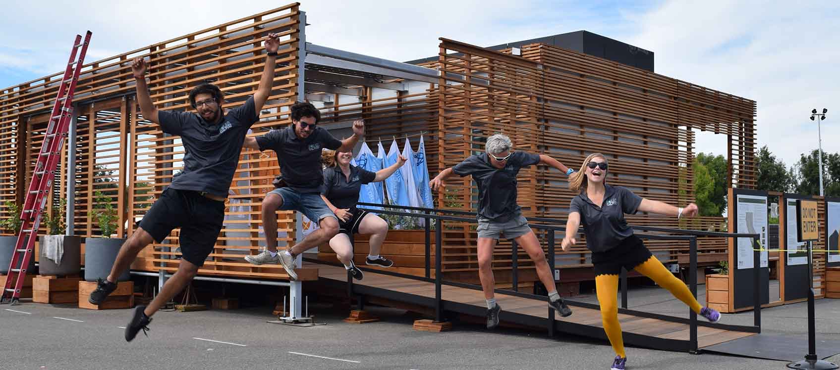 Photo of a  Solar Decathlon team jumping in front of its house.