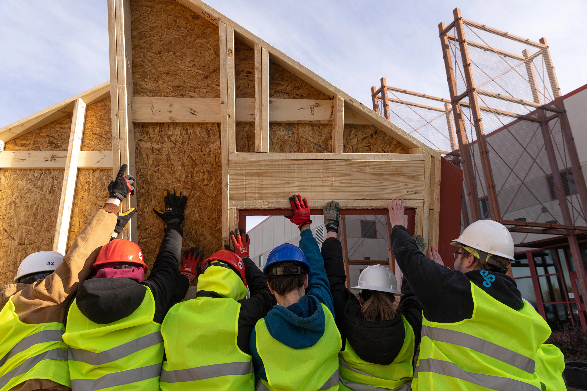 A photo of a team working together to raise a wall of a house