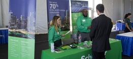 Photo of a man in a business suit speaking with two people at a sponsor booth.