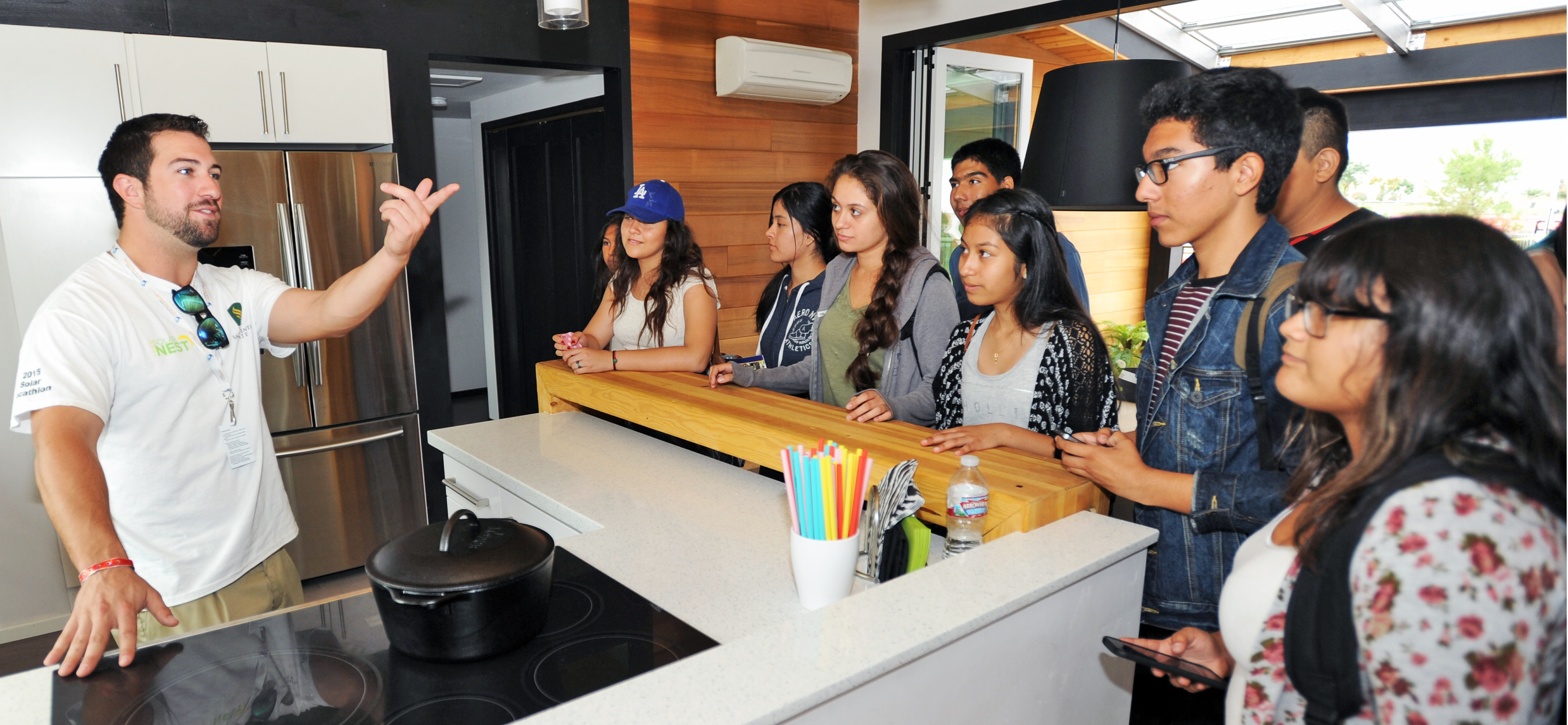 Solar Decathlon Pathways banner image. Blake Boyles (left) speaks to students from Bell Gardens High School in the kitchen of California State University, Sacramento, at the U.S. Department of Energy Solar Decathlon at the Orange County Great Park, Irvine, California, Oct. 15, 2015.