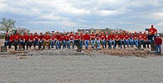 Photo of members of the University of Louisville, Ball  State University, and University of Kentucky Solar Decathlon team sitting in a  row on a long beam.
