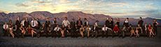 Photo of members of the University of Nevada Las Vegas  Solar Decathlon 2013 team seated on a long couch. Desert mountains are in the  background.