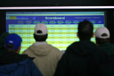 Photo of people looking at an electronic scoreboard. 