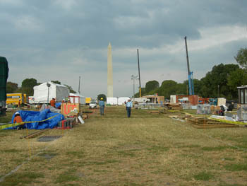 Photo of the Solar decathlon solar village taking shape on the National Mall. Three construction cranes are seen with the Washington Monument in the background.