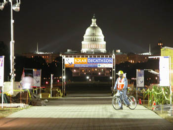 Photo of man on bicycle in front of Capitol building at night.