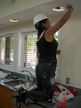 Photo of a woman sanding ceiling.
