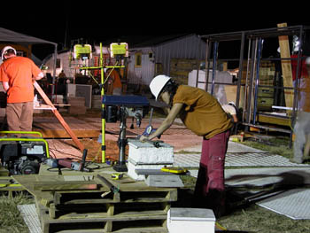 Photo of woman drilling at night near a construction light.