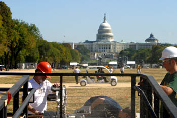Photo of men working on a ramp, electric vehicle and Capitol in background.