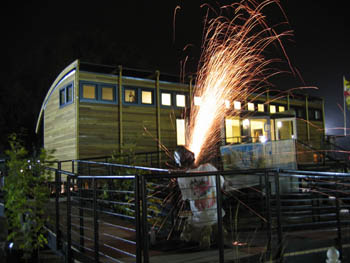 Photo of sparks flying as man uses tool on railing at night.