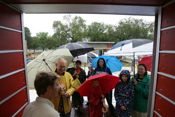 Photo of a group of people with umbrellas looking in a home.