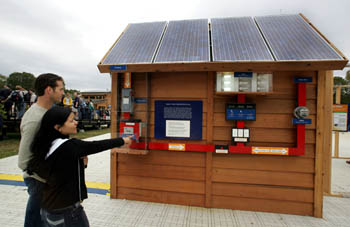 Photo of a man and a woman standing and pointing at a solar electricity display.