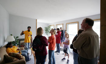 Photo of ten people standing inside a living room.
