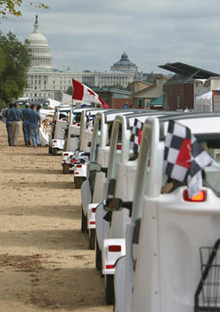 Photo of a line of electric vehicles heading down the Mall toward the Capitol building.