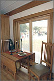 Photo of dining table and chairs on wood floor next to wood-trimmed window.