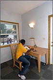 Photo of woman sitting at table next to window.