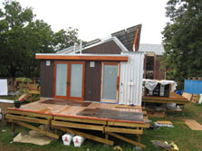 Photo of the side view of Maryland's Solar Decathlon house, which has another large deck and two glass doors leading into the house.