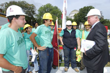 Photo of Secretary Bodman in a suit and wearing a hardhat, talking to about 10 team members from Santa Clara University.