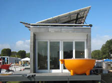 Photo of a half-sphere-shaped hot tub sitting on the deck of the house from the University of Texas at Austin. Tubes extend from the hot tub to the rear of the house, where a coil provides a way to heat the water.