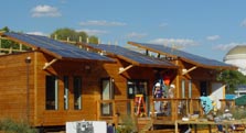 Photo of the exterior of a solar house under construction, showing three blocks of solar panels on the roof.
