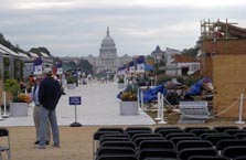 Photo looking down the walkway between the solar houses. The U.S. Capitol building looms in the background, while chairs are set up in the foreground.