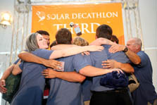 Photo of ten team members hugging beneath a third place banner.