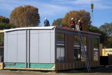 Photo showing the exterior of a square solar home unit with the porch and landscaping removed.