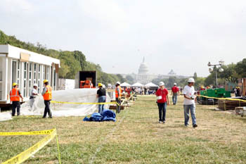Photo of several people on the path that runs down the National Mall, and all are wearing hard hats. The Capitol building is in the background and to one side is the home from the Universidad de Puerto Rico.
