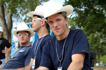 Photo of three young men wearing hard hats that are fitted into cowboy hats.