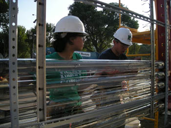 Photo of a young woman holding a glass tube in place as a young man secures it in place. A total of five glass tubes are mounted on a metal rack.